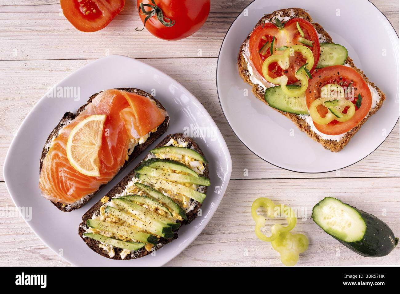 Panini con formaggio, trota salata, pomodoro, cetriolo su fondo bianco in legno Foto Stock