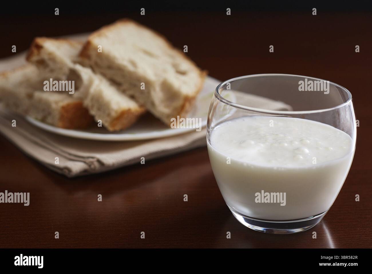 Tazza di vetro con kefir su un tavolo scuro e sfondo. Pane fatto a mano sullo sfondo Foto Stock Tazza di vetro con kefir su un tavolo scuro e sfondo. Pane fatto a mano sullo sfondo Foto Stock