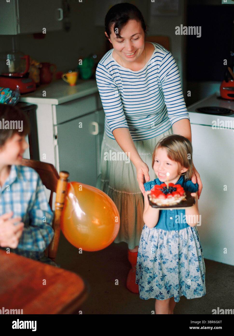 Sorella che porta la torta di compleanno per fratello Foto Stock