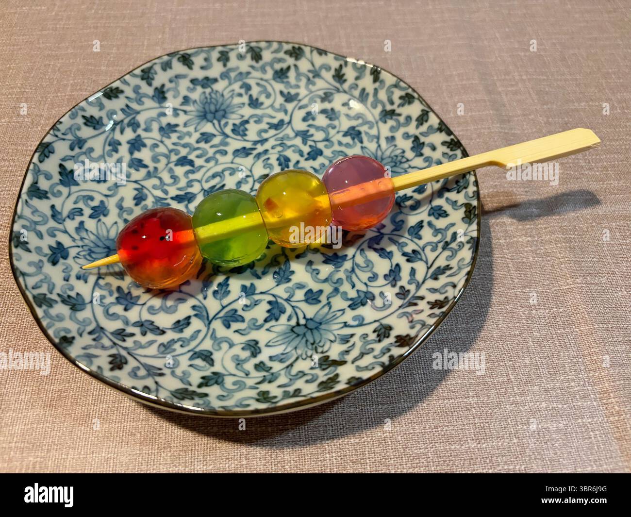 Gelatina colorata a forma di piccole palline rotonde, servita su uno spiedino. Foto Stock