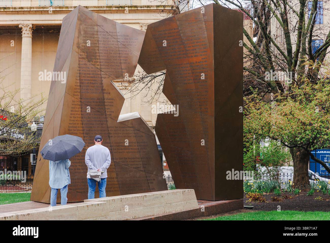 Una coppia sta di fronte al memoriale dell'olocausto sotto la pioggia Foto Stock