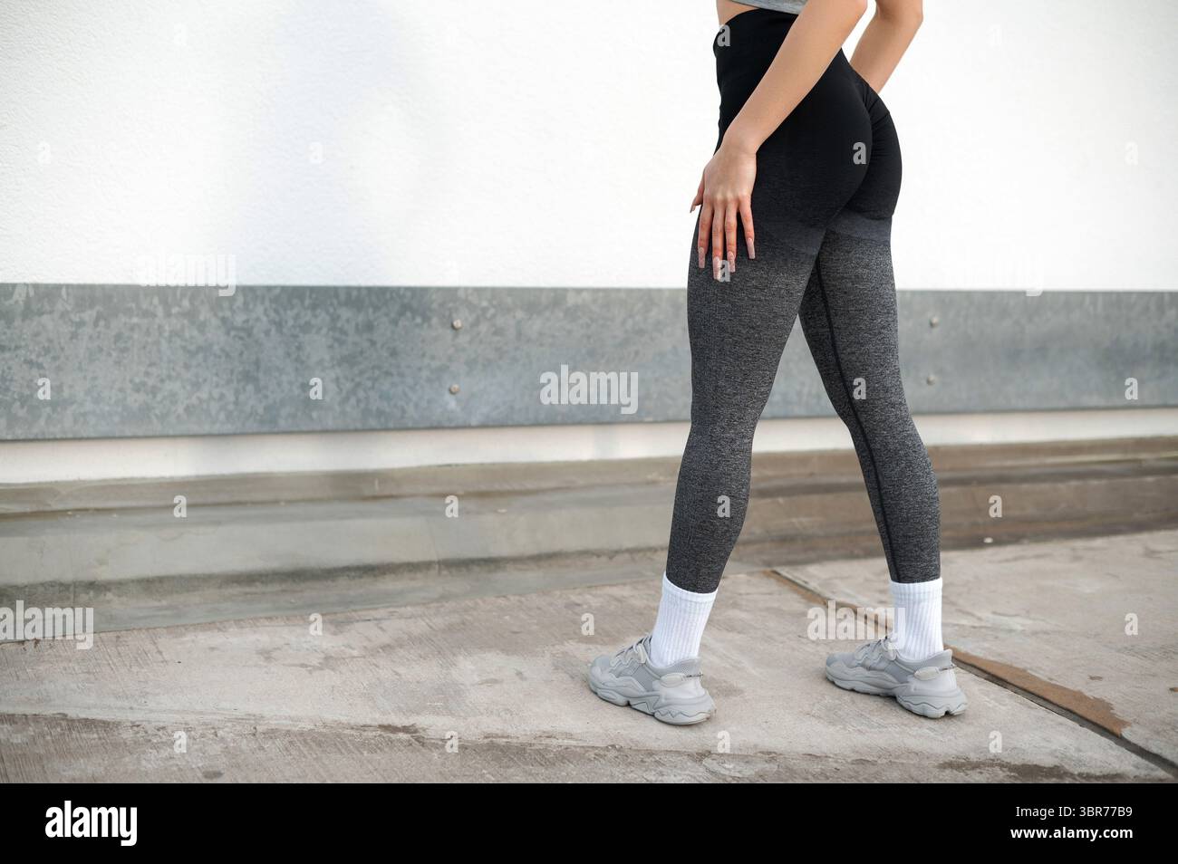 Donna in grigio leggings e sneakers all'aperto Foto Stock