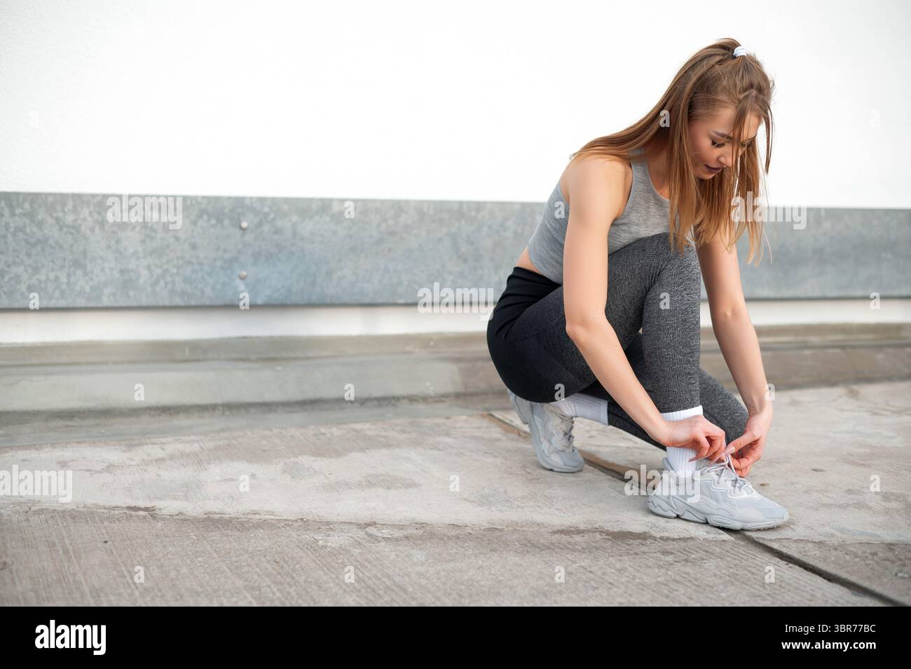Donna che lega le scarpe prima di allenarsi Foto Stock