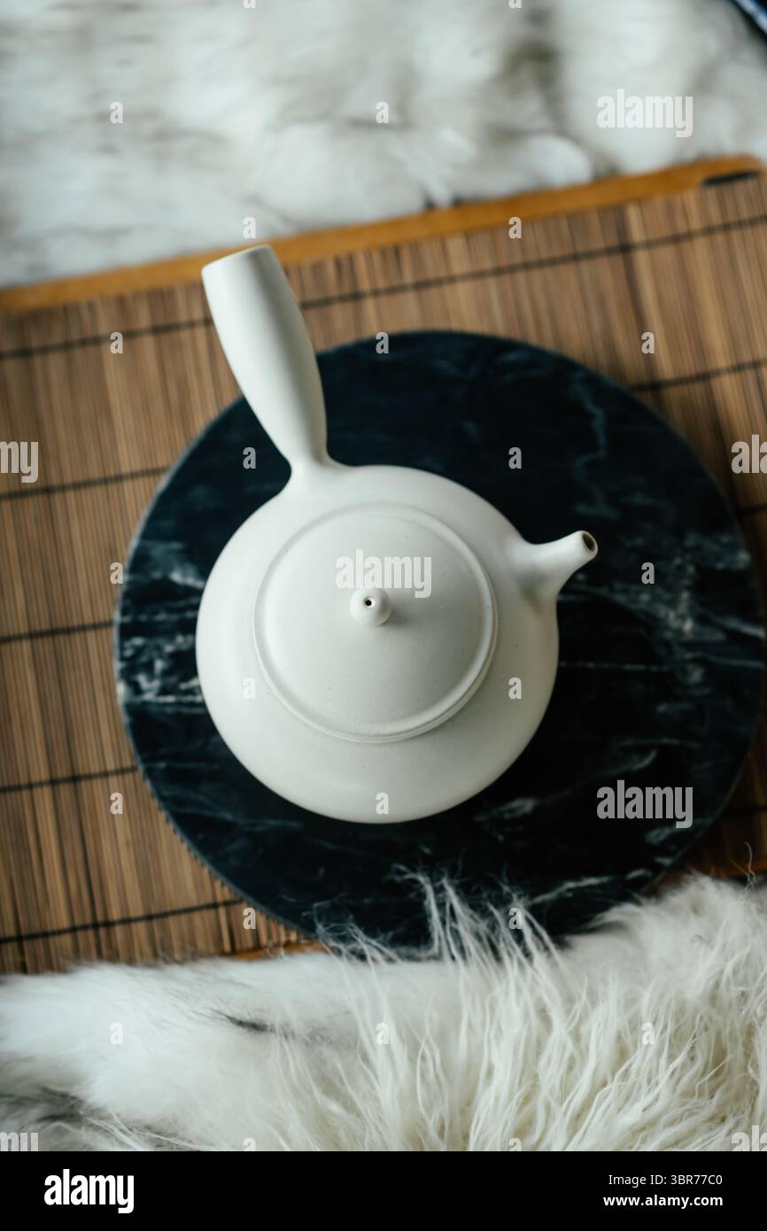 Teiera Kyusu giapponese bianca minimalista su vassoio in marmo e tappetino in bambù Foto Stock