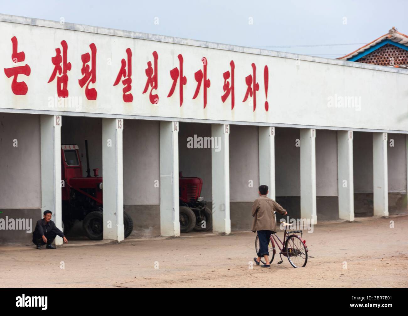 Garage per veicoli agricoli con uno slogan in cima, South Hamgyong, Hamhung, Corea del Nord Foto Stock