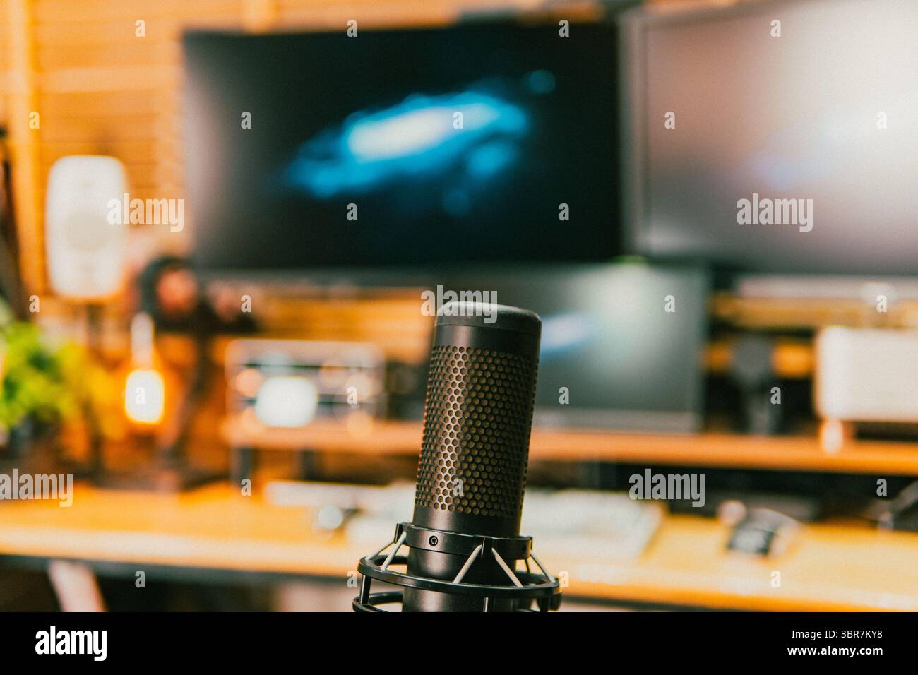 Un accogliente ambiente di lavoro cinematografico con schermi luminosi, illuminazione soffusa e accessori tecnologici. Perfetto per concetti tecnici o di produttività. Foto Stock