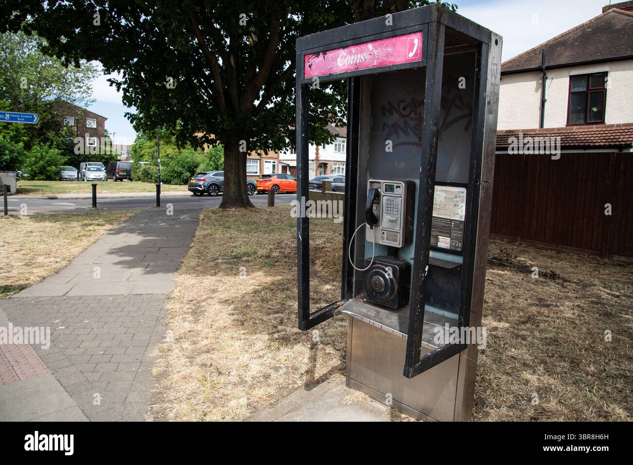 Una cabina telefonica pubblica del Regno Unito abbastanza moderna con una struttura in vetro e metallo, che mostra segni di usura e abbandono, un apparecchio urbano che sbiadisce in disuso. Foto Stock
