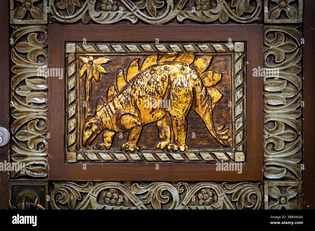 WASHINGTON DC - le porte d'ingresso ornate in legno del Reptile Discovery Center presentano sculture in rilievo d'oro di stegosauro e altri rettili, con maniglie delle porte modellate come serpenti intrecciati. Le porte decorative, risalenti al 1931, facevano parte del progetto completo dell'architetto Albert L. Harris per l'edificio, che includeva il famoso mosaico di stegosaurus creato attraverso la collaborazione con il paleoartista Charles R. Knight e il pioniere del cemento John Joseph Earley. Le porte completano lo stile architettonico bizantino-romanico dell'edificio e riflettono l'approccio dell'era Progressista alla fusione scientifica Foto Stock