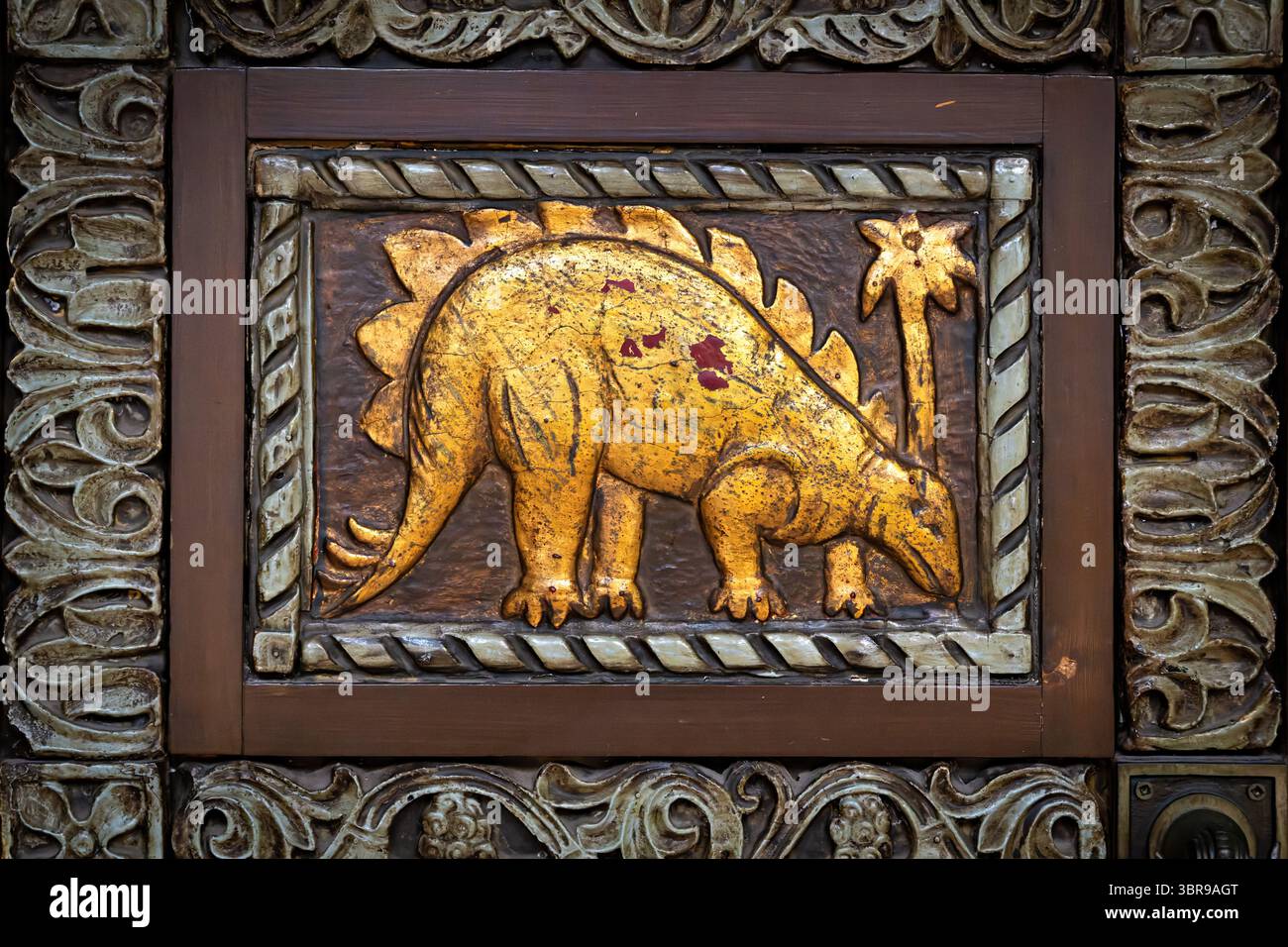 WASHINGTON DC - le porte d'ingresso ornate in legno del Reptile Discovery Center presentano sculture in rilievo d'oro di stegosauro e altri rettili, con maniglie delle porte modellate come serpenti intrecciati. Le porte decorative, risalenti al 1931, facevano parte del progetto completo dell'architetto Albert L. Harris per l'edificio, che includeva il famoso mosaico di stegosaurus creato attraverso la collaborazione con il paleoartista Charles R. Knight e il pioniere del cemento John Joseph Earley. Le porte completano lo stile architettonico bizantino-romanico dell'edificio e riflettono l'approccio dell'era Progressista alla fusione scientifica Foto Stock