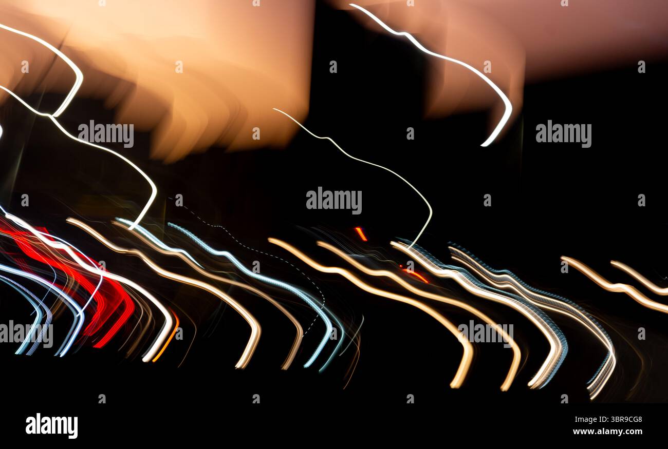 Foto notturna di un viale di edifici con strisce colorate. Le strisce sono il riflesso delle luci e dei lampioni dell'auto. La foto ha una a scura Foto Stock