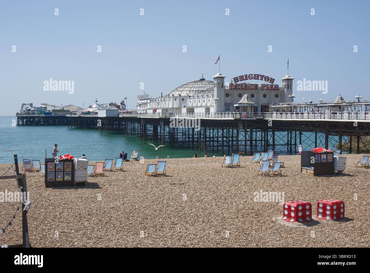 Brighton Palace Pier e spiaggia di ciottoli a Brighton nell'East Sussex, Inghilterra. Con la gente che si gode il sole. Foto Stock