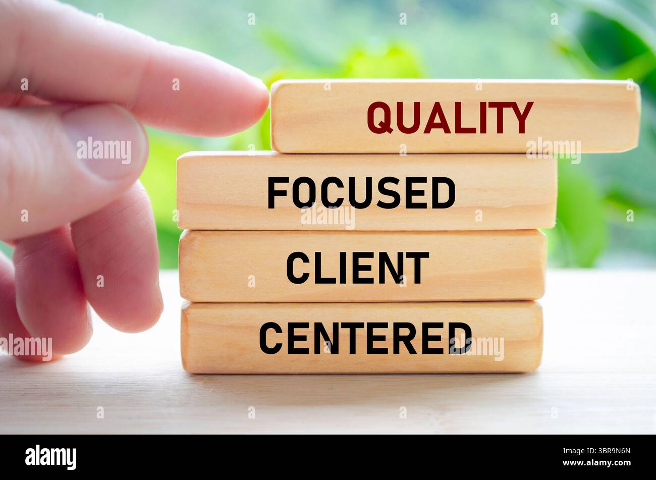 Il testo incentrato sulla qualità del cliente su blocchi di legno tenuti a mano mostra una dedizione alla comprensione e al servizio dei clienti. Foto Stock