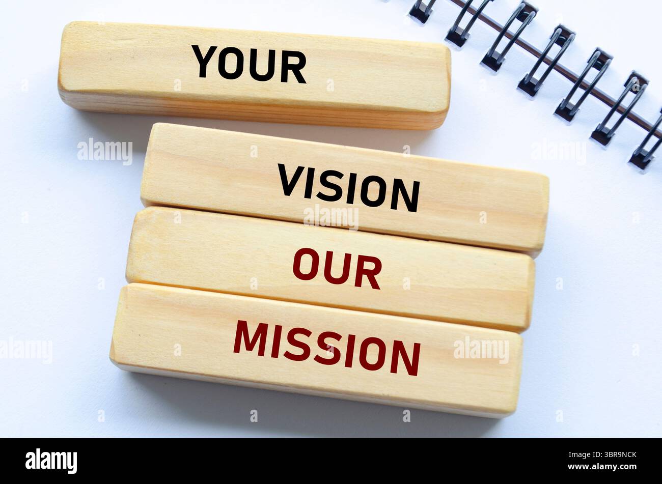 La vostra visione il nostro testo della missione su blocchi di legno e notebook sottolinea l'allineamento con gli obiettivi del cliente e lo scopo condiviso. Foto Stock
