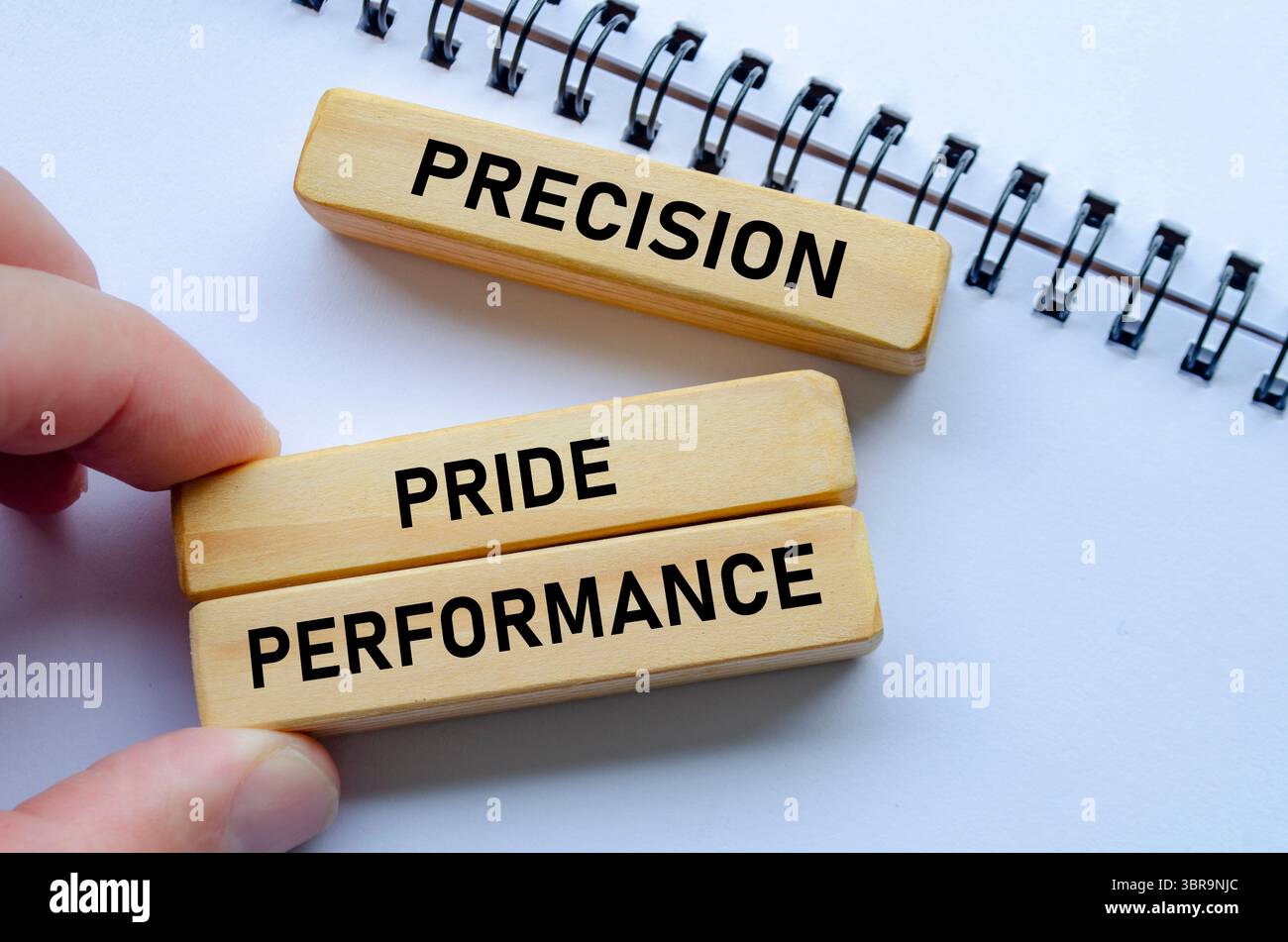 La precisione attraverso le prestazioni mostrate su blocchi di legno sopra un blocco note indica l'importanza della precisione per raggiungere il successo. Foto Stock