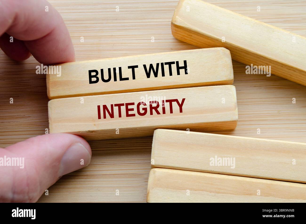 Costruito con testo di integrità su blocchi di legno tenuti a mano riflette fiducia, forza e valori etici in ogni azione. Foto Stock