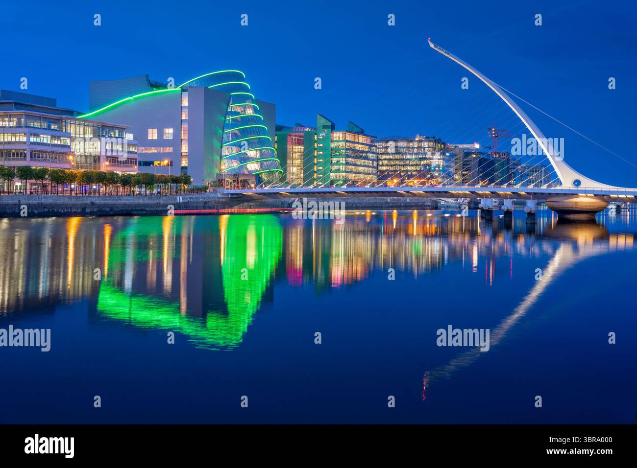 Il Centro Congressi di Dublino e il Ponte Samuel Beckett si illuminano all'ora blu, con riflessi scintillanti sul fiume Liffey e una serata blu intenso Foto Stock