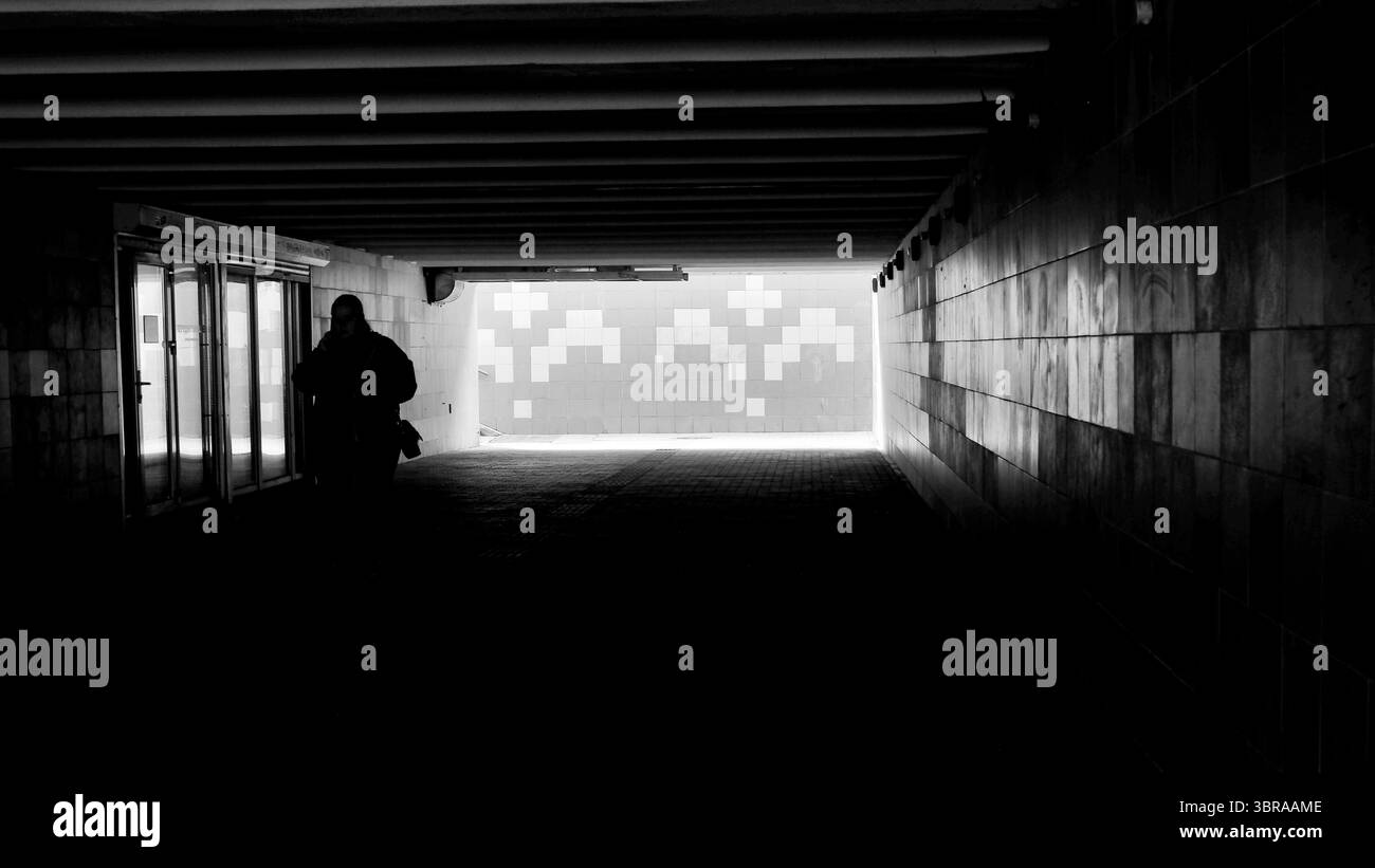 Una misteriosa silhouette si avventura attraverso un corridoio oscuro in un ambiente luminoso. Foto Stock