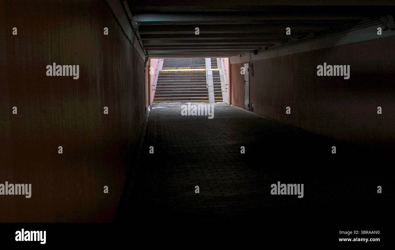 Un tunnel buio rivela scale che salgono verso la luce, creando un senso di speranza. Foto Stock