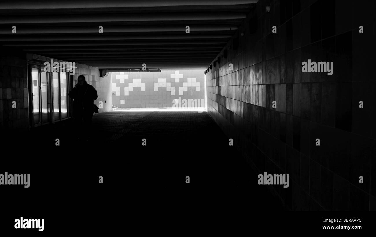 Una misteriosa silhouette si avventura attraverso un corridoio oscuro in un ambiente luminoso. Foto Stock