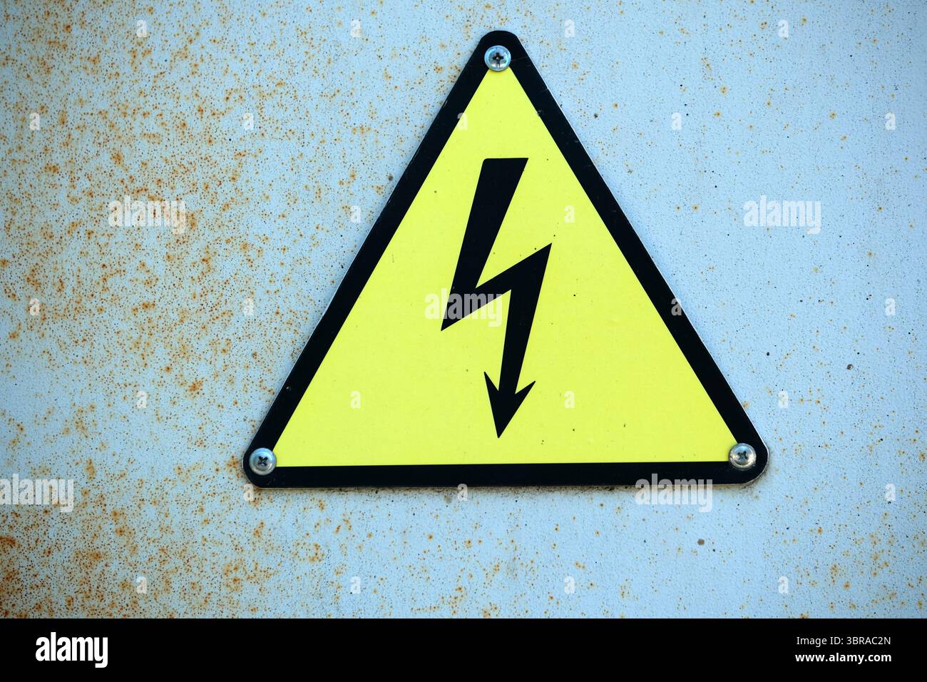 Un segnale giallo brillante con un fulmine segnala i pericoli elettrici. Foto Stock