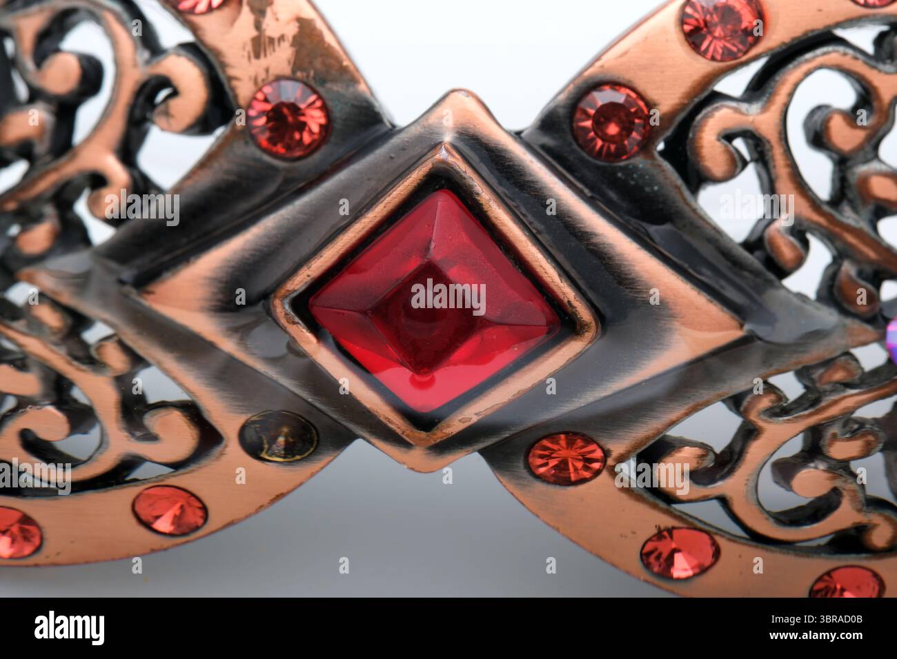 Uno splendido bracciale presenta disegni intricati decorati con luccicanti gemme rosse. Foto Stock