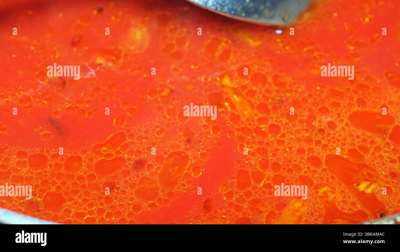 Un ricco brodo rosso bollicine con spezie che danno vita a aromi accoglienti. Foto Stock