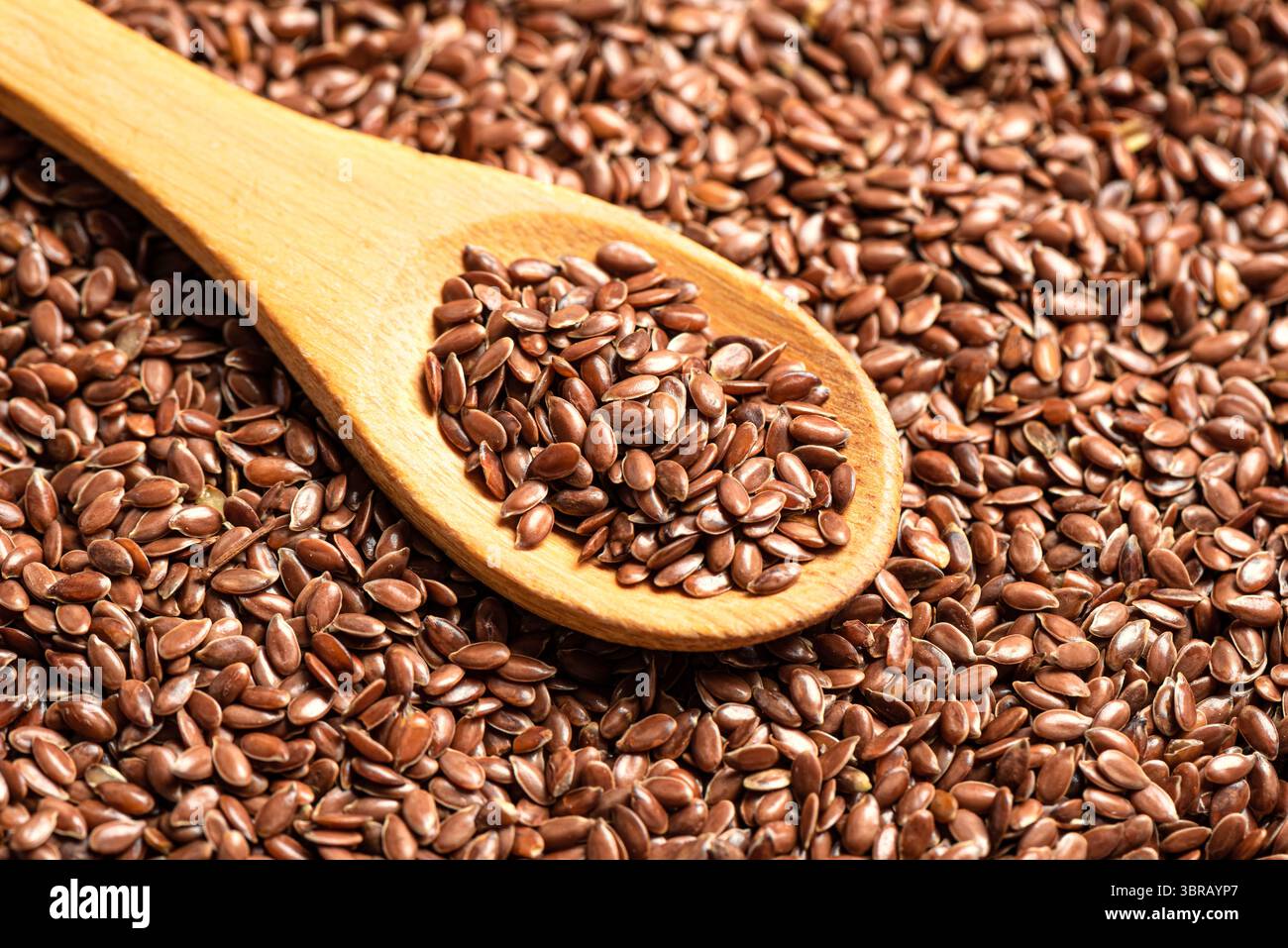 Semi di lino su cucchiaio di legno o semi di lino come sfondo, semi di lino marrone da vicino. Mangiare sano. Prodotto biologico. Foto Stock