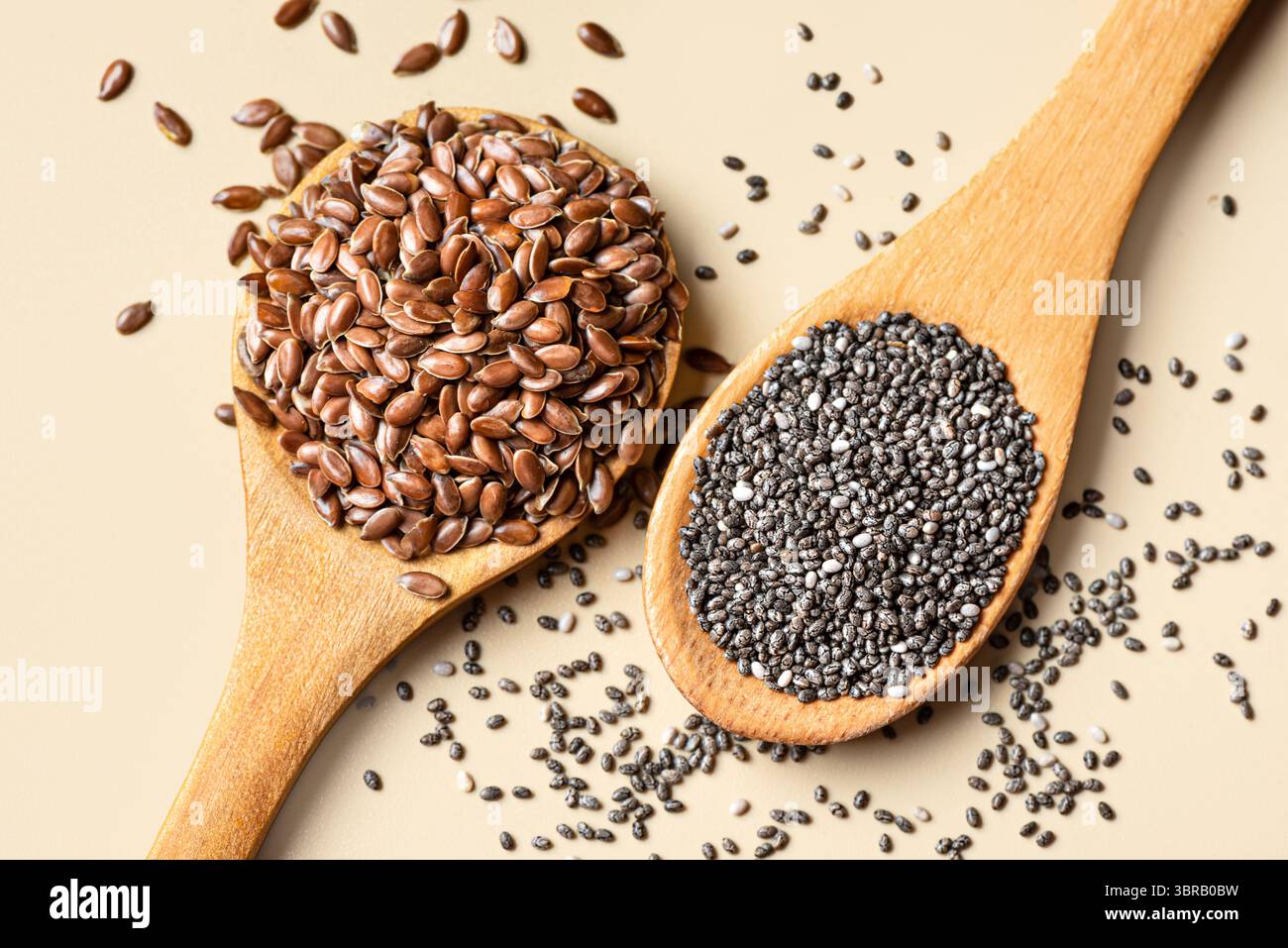 Semi di lino e semi di chia su cucchiai di legno e sfondo beige estremamente ravvicinato, vista dall'alto. Alimentazione sana, superfood naturale biologico. Foto Stock