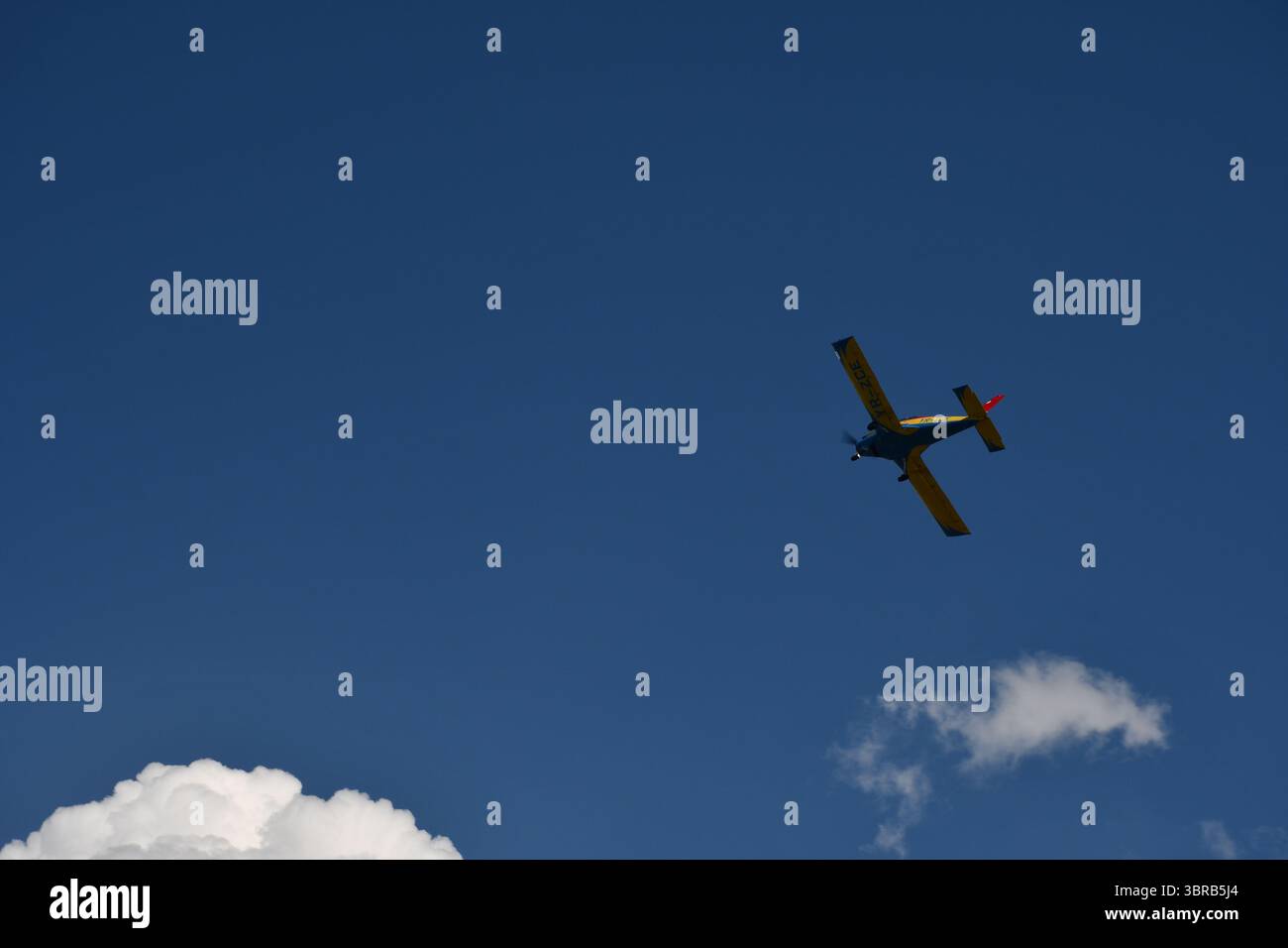 Un aereo aerobatico rumeno esegue una brusca manovra bancaria sopra le nuvole durante uno spettacolo aereo, mostrando agilità e controllo sotto il blu profondo Foto Stock