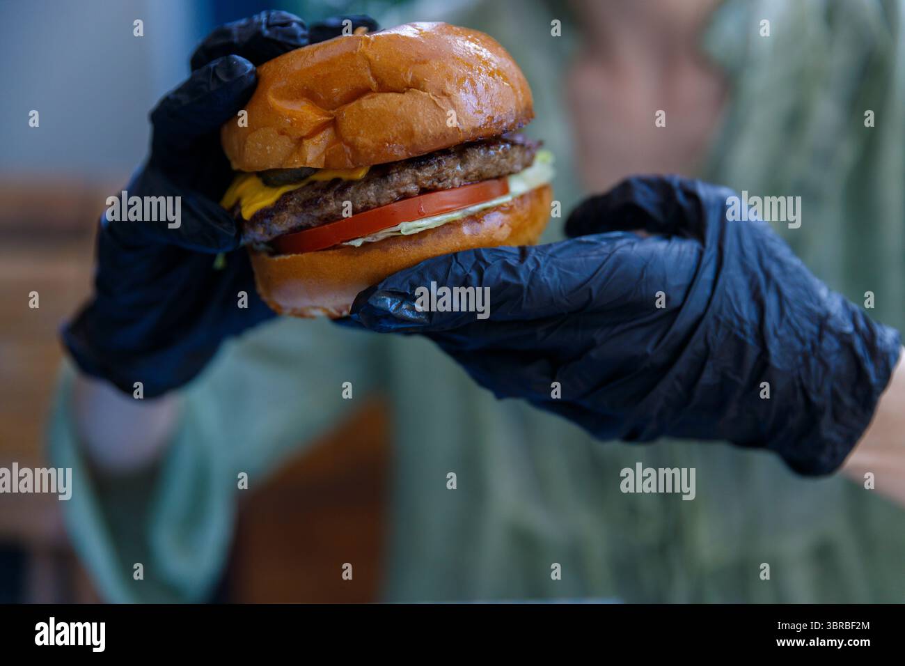 Delizioso Cheeseburger presentato con attenzione all'igiene in un ambiente informale, con ingredienti freschi e appetitosi Foto Stock