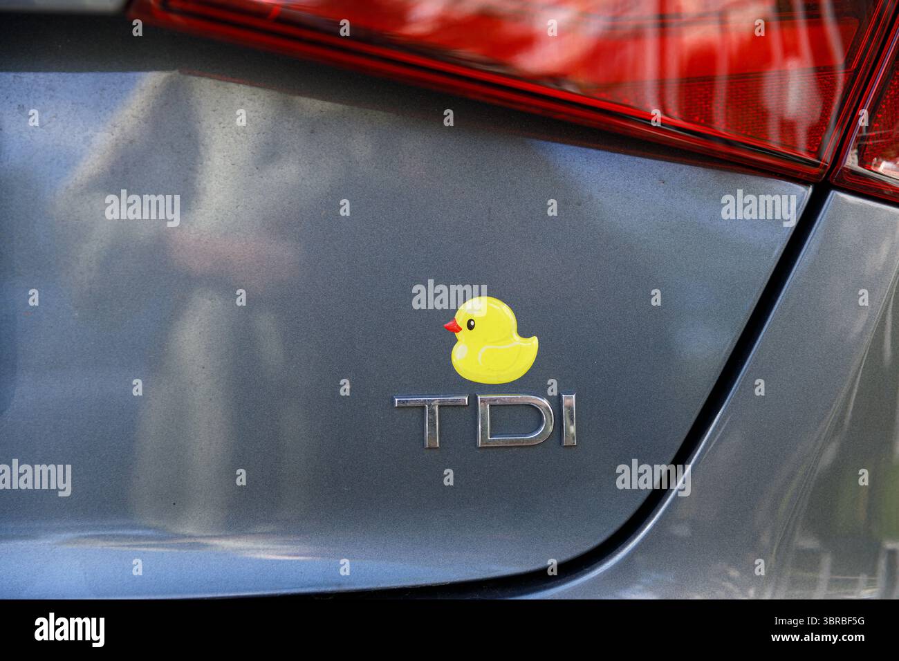 Un tocco giocoso: Primo piano del paraurti posteriore di un'auto con un simpatico adesivo in gomma e il logo TDI, che aggiunge un elemento stravagante Foto Stock
