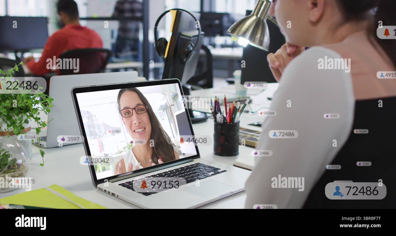 Lavoratore pendente che indossa il giubbotto per partecipare a una riunione remota in un ufficio aperto con laptop e spazio per fotocopie Foto Stock