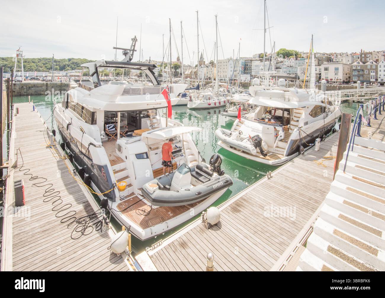 L'obiettivo centrale è un grande yacht con un gonfiabile più piccolo all'interno di un'affollata scena marina al porto di Guernsey, Isole del Canale. Foto Stock