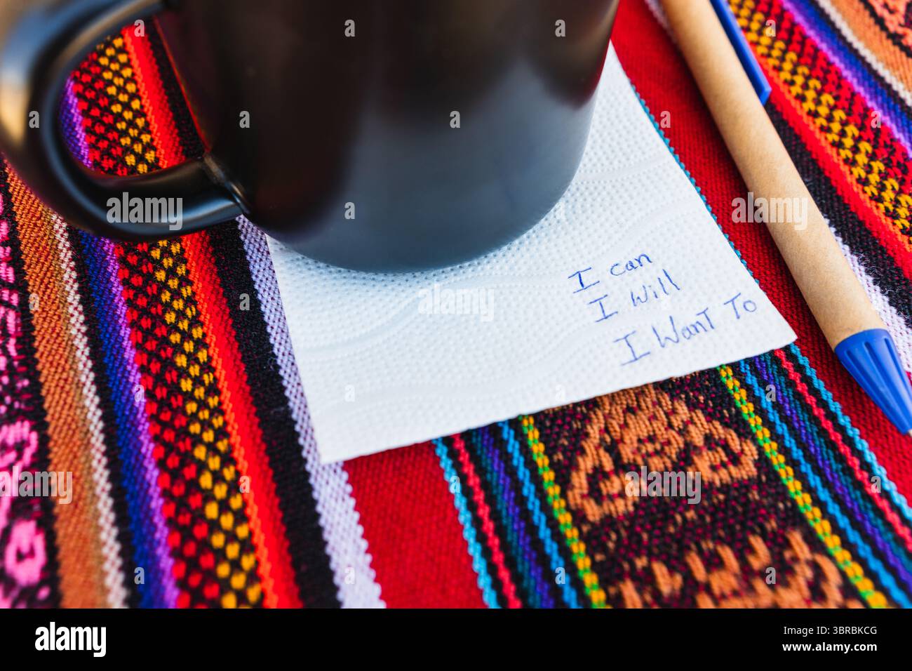 Tazza da caffè con scritto un biglietto che dice che posso farlo voglio su un tavolo colorato con tessitura Inca. Foto Stock