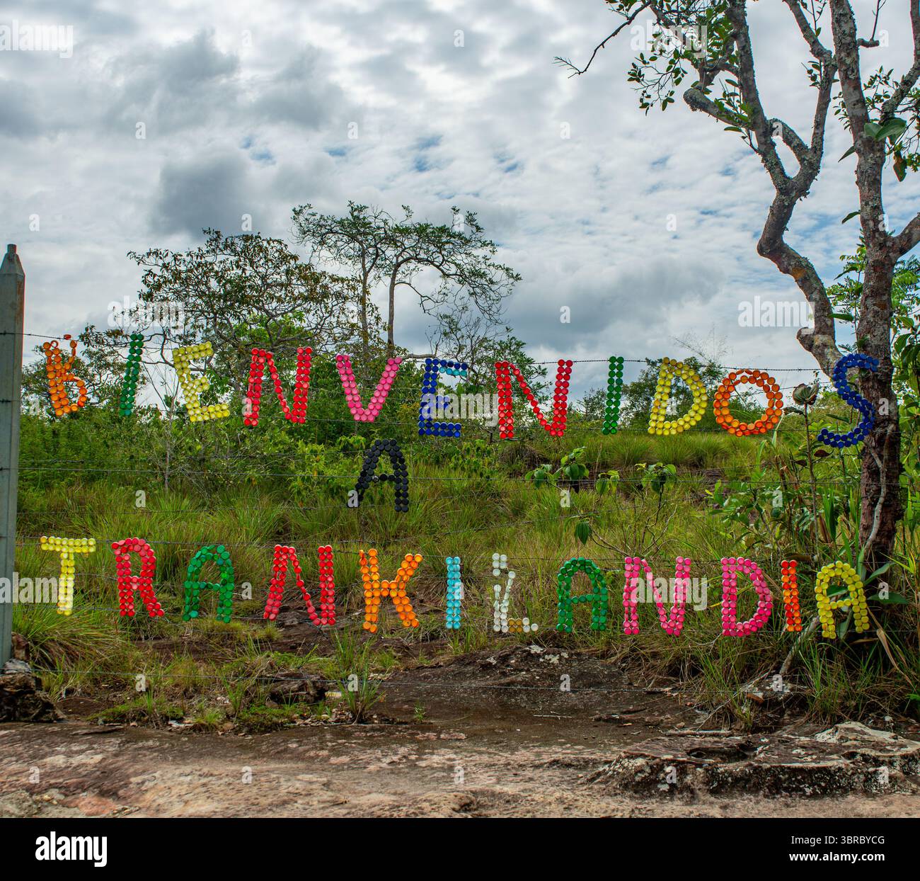 Un vibrante segno fatto di materiali colorati che recita 'Bienvenidos a Tranquilandia' a Guaviare, Colombia, circondato da vegetazione lussureggiante e cieli nuvolosi. Foto Stock