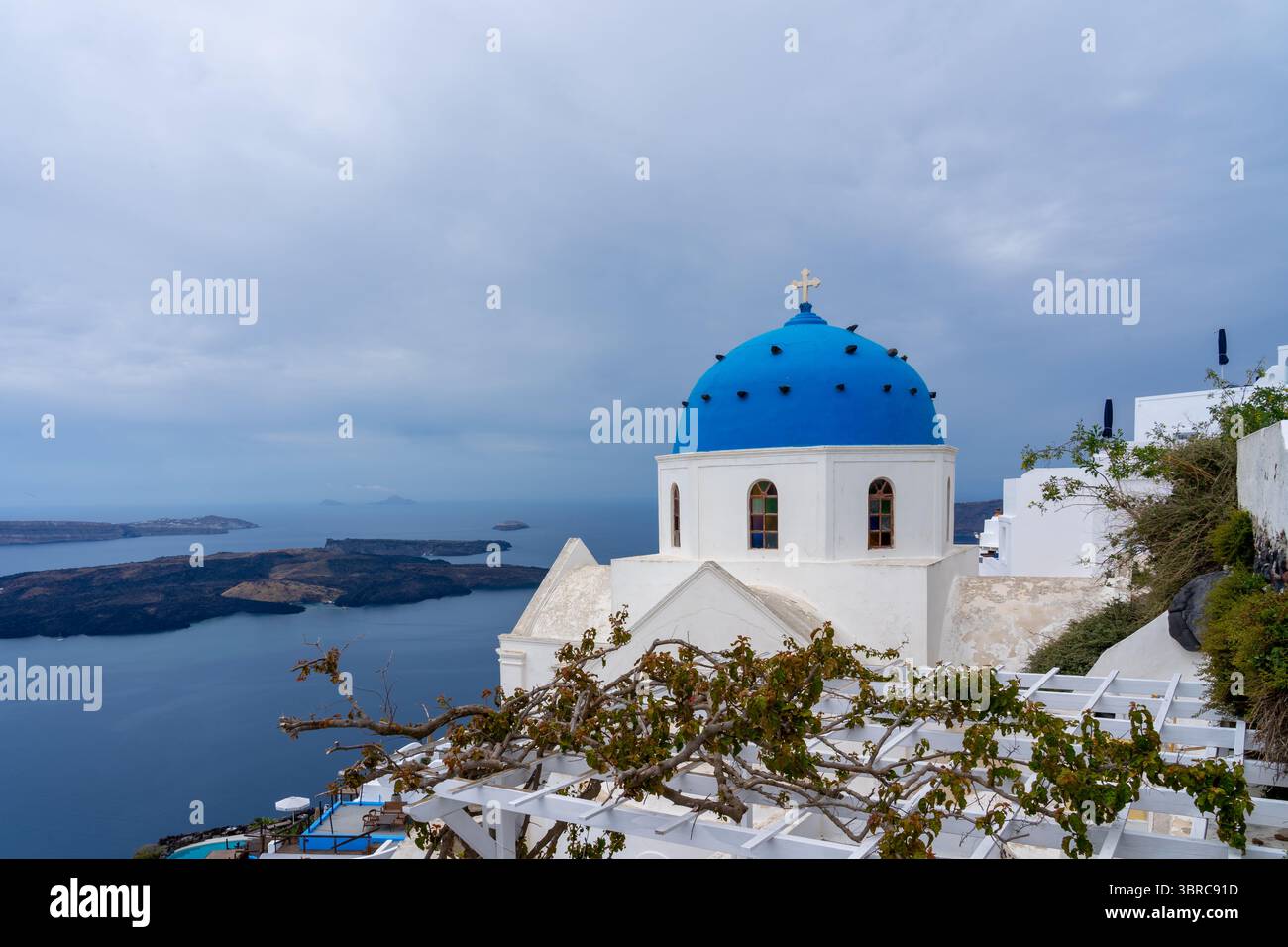 Chiesa della Risurrezione del Signore con vite su traliccio in primo piano a Fira, Santorini, Grecia. Foto Stock