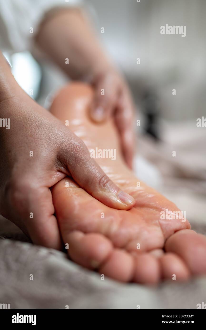 Massaggio rilassante ai piedi per un uomo, concentrandosi su come alleviare lo stress, migliorare la circolazione sanguigna e promuovere il benessere generale. Foto Stock