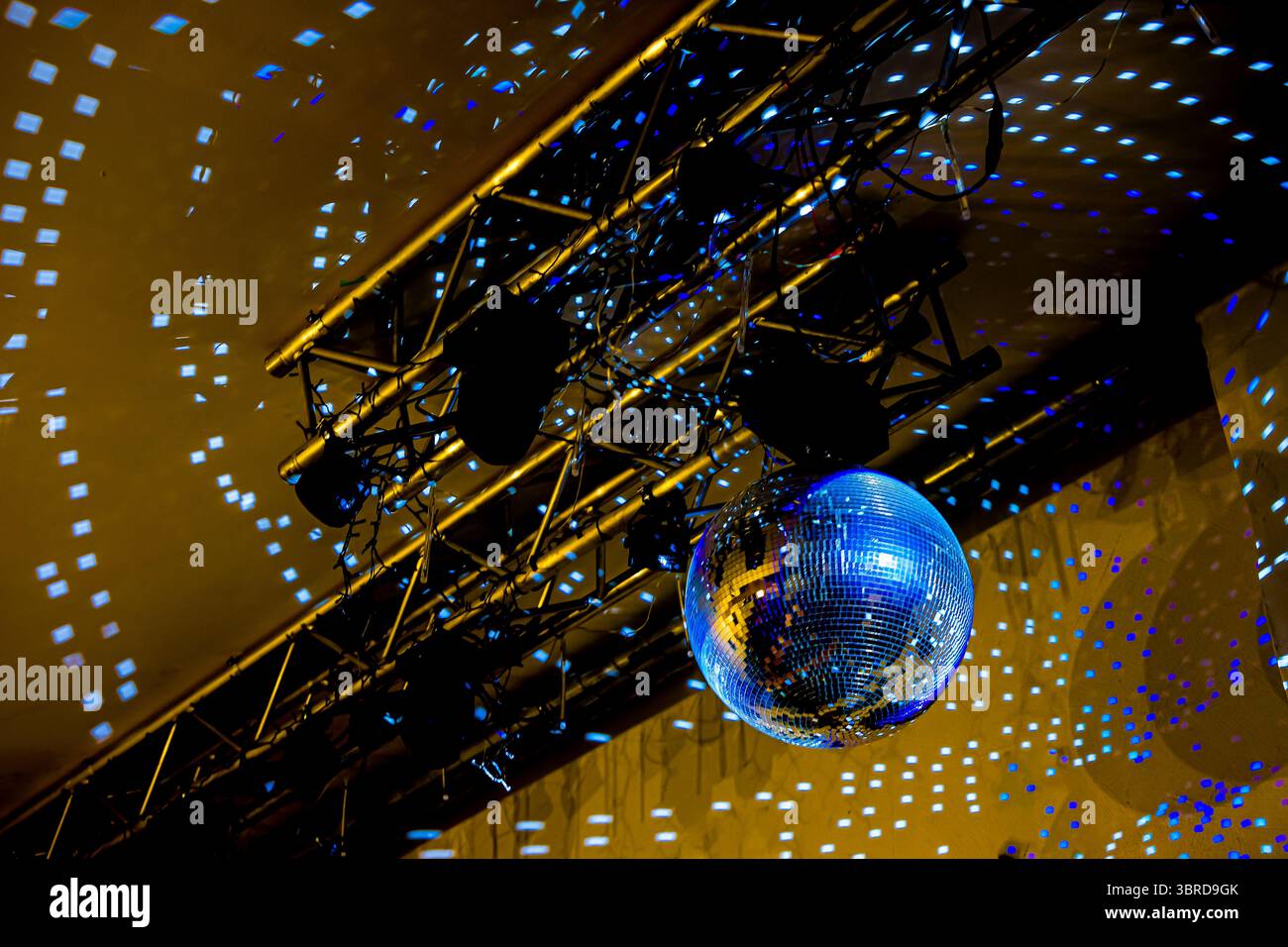 Palla da disco lucida appesa a una trave metallica. La disco Ball riflette la luce blu e bianca. Festa, evento di ballo o atmosfera da night club. Foto Stock
