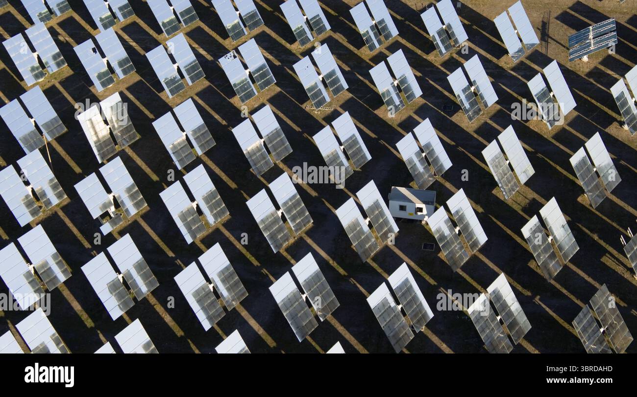 Vista aerea di specchi solari scintillanti si estendono attraverso il paesaggio arido, riflettendo il cielo luminoso e gettando ombre scure, Almería, Andalusia, Spagna. Foto Stock