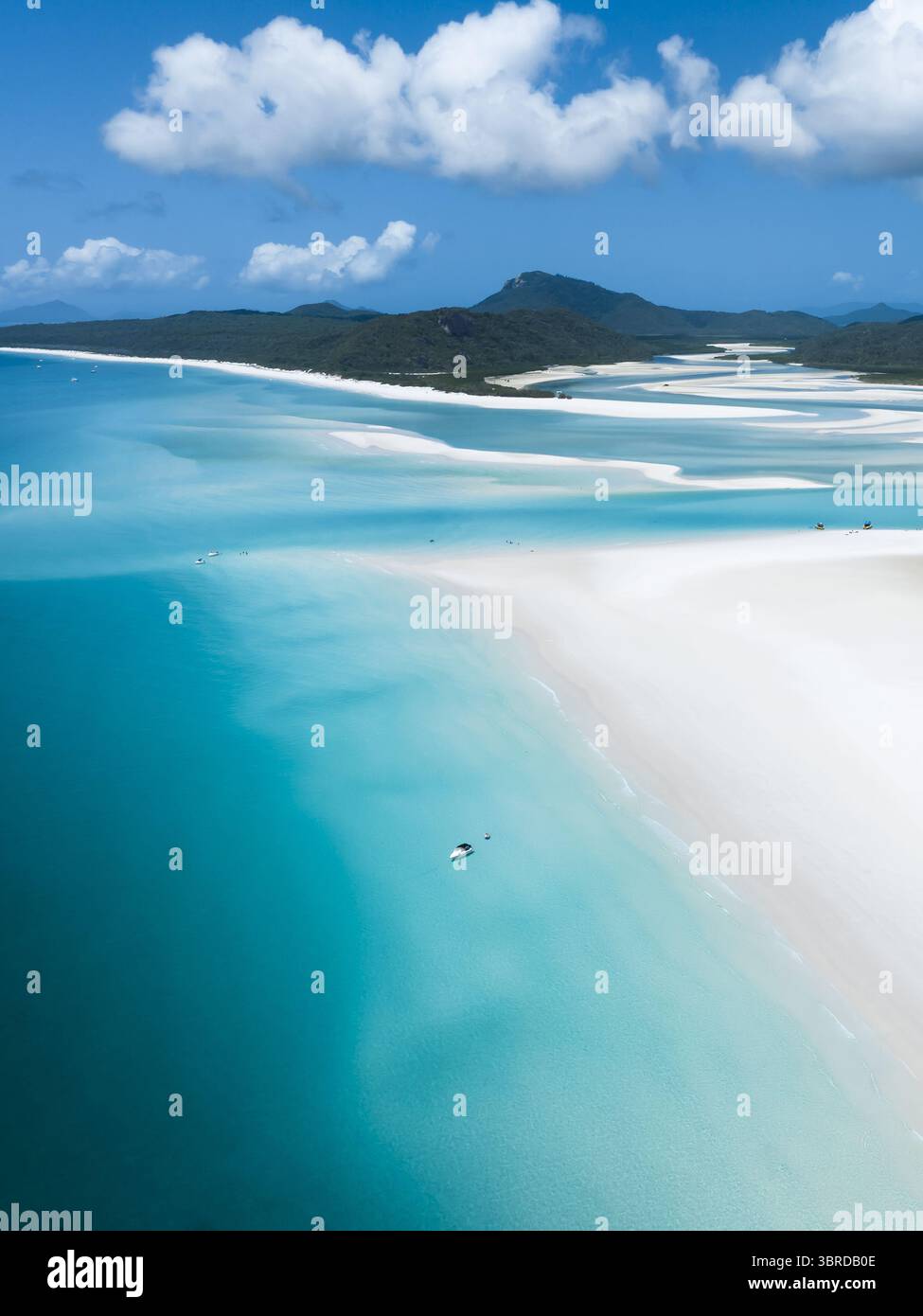 Vista aerea delle sabbie bianche che incontrano le acque turchesi, creando schemi ipnotici sullo sfondo delle lussureggianti isole del Queensland, Australia. Foto Stock