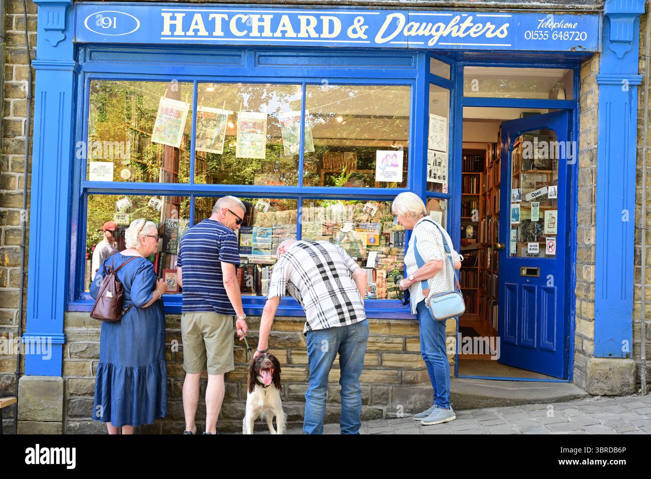 Quattro pensionati che guardano in una vetrina con un cane, Haworth, West Yorkshire Foto Stock