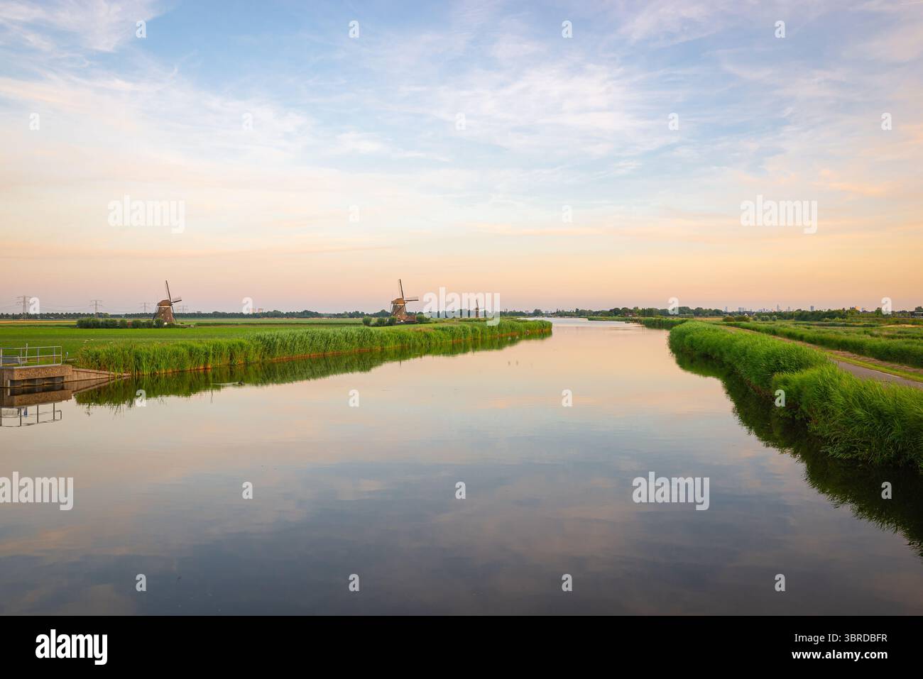 Ampia vista sulle calme acque del fiume rotte, Paesi Bassi occidentali, con mulini a vento in lontananza. Foto Stock
