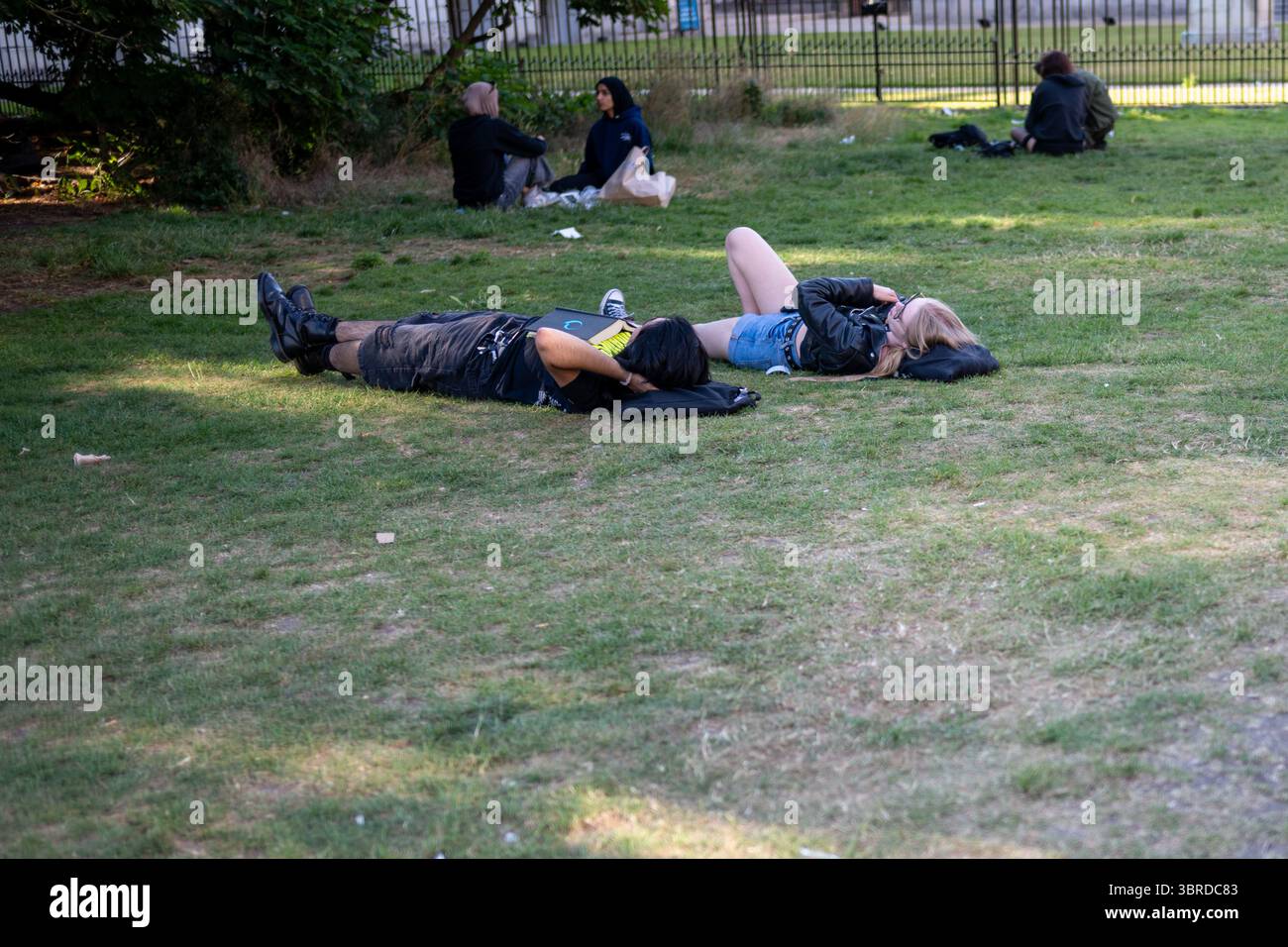 Le persone si rilassano sull'erba in un parco cittadino in una calda giornata estiva a Cambridge, Regno Unito Foto Stock