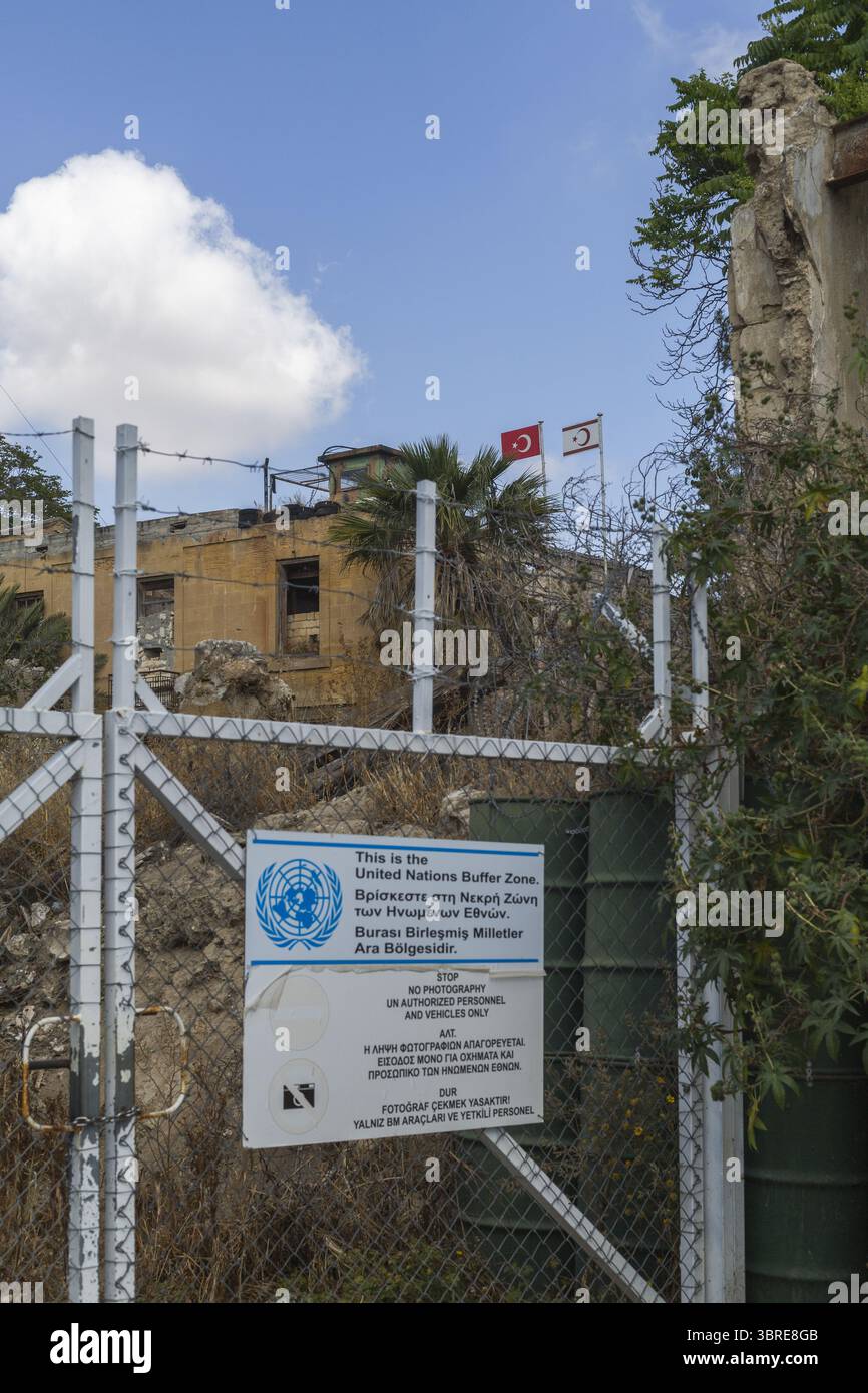 Lefkosia, Cipro - 25 giugno 2025: Vista della barriera della zona cuscinetto delle Nazioni Unite, dove il metallo intemprato incontra la terra arida sotto un vasto cielo disseminato di nuvole. Foto Stock