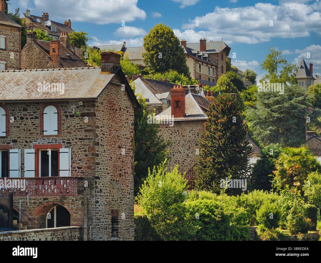 Affascinanti case di pietra in un lussureggiante villaggio di campagna sotto il cielo blu della Francia Foto Stock