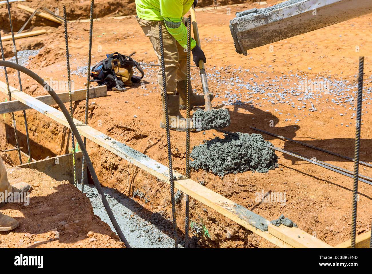 I lavoratori eseguono il versamento di calcestruzzo nel cantiere durante la costruzione di nuove case in giornata di lavoro Foto Stock