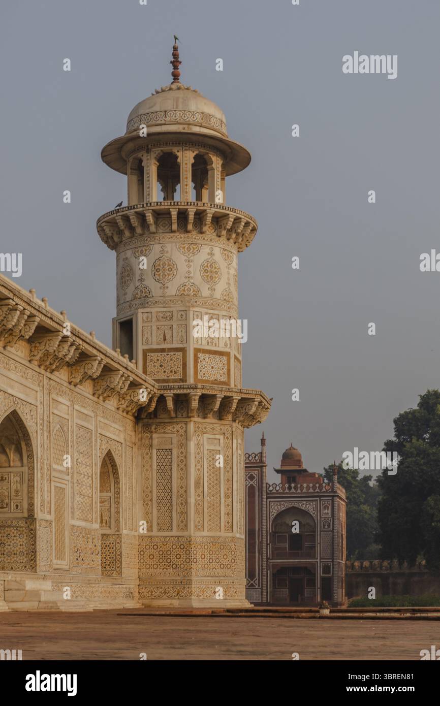 Ammira gli intricati dettagli in marmo che adornano la torre della tomba, immersi nel caldo bagliore dell'alba, che getta ombre morbide sulla pietra, Agra, Uttar Pradesh, India. Foto Stock