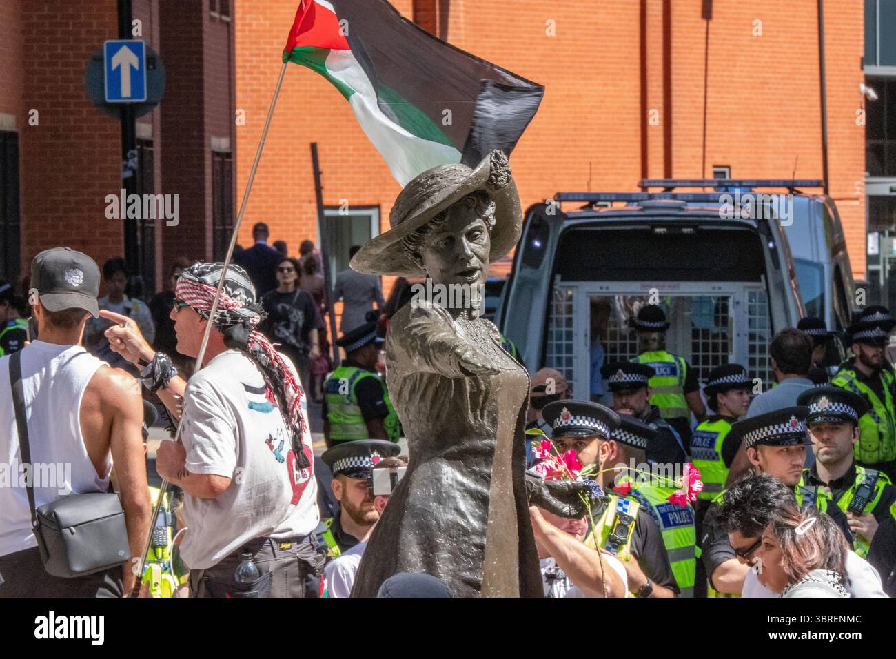 Statua di Emmeline Pankhurst con in background persone collocate in furgoni della polizia dopo essere state arrestate per aver tenuto cartelli a sostegno dell'azione palestinese. Palestine Action arresta Manchester UK a "difendere la nostra protesta delle giurie" a sostegno del gruppo vietato Palestine Action . Più di una dozzina di manifestanti sono stati portati via dalla polizia in furgoni dopo essere stati rimossi da una protesta in piazza San Pietro dalla statua di Emmeline Pankhurst. I parlamentari britannici hanno votato per vietare l'azione palestinese come gruppo terroristico. Alla protesta che ha portato agli arresti si sono svolti cartelli d'azione per la Palestina. Molti di quelli portati via eravamo noi Foto Stock