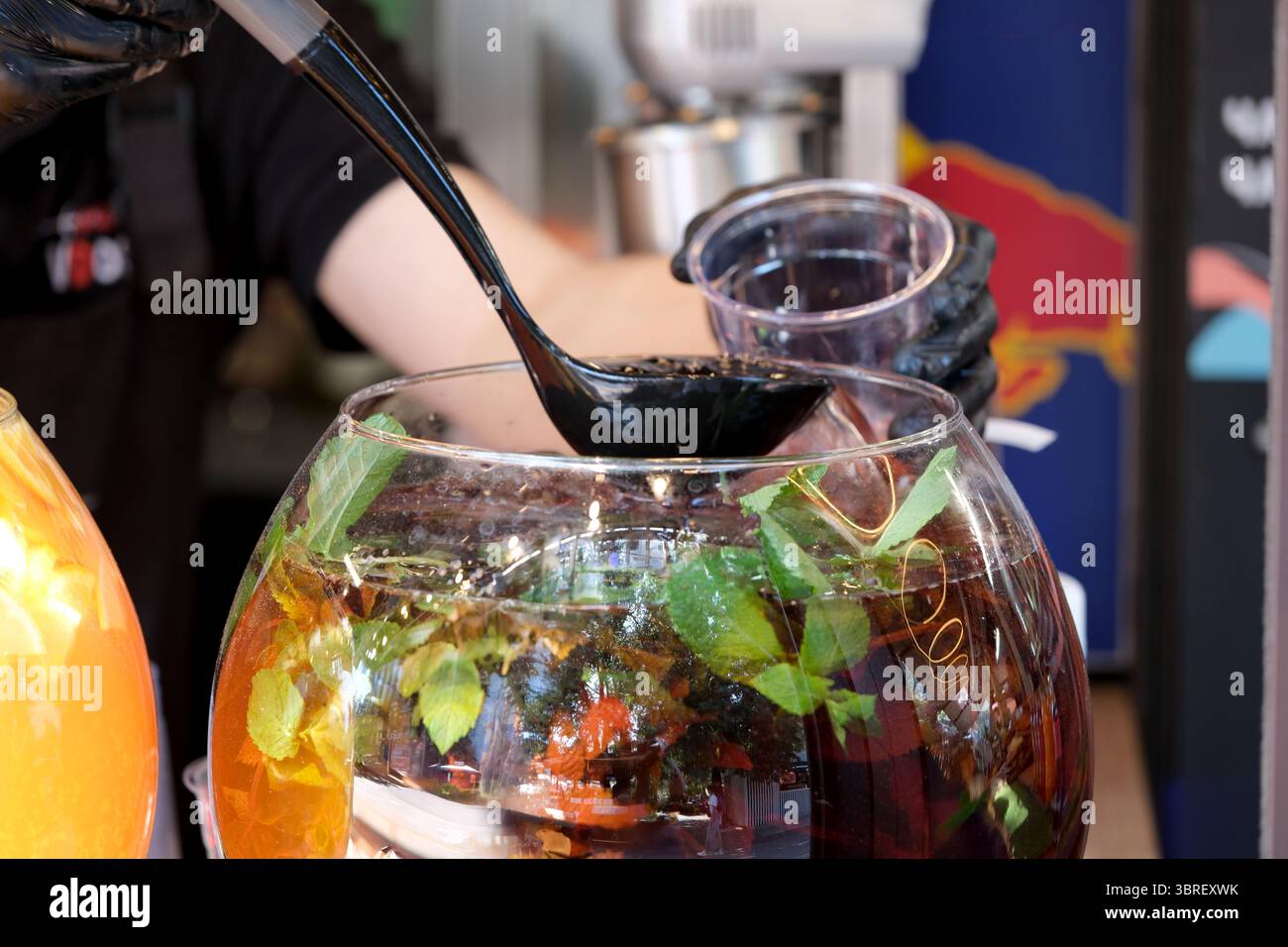 Un venditore mescola sapientemente un vivace punch di frutta, mostrando ingredienti e sapori freschi. Foto Stock