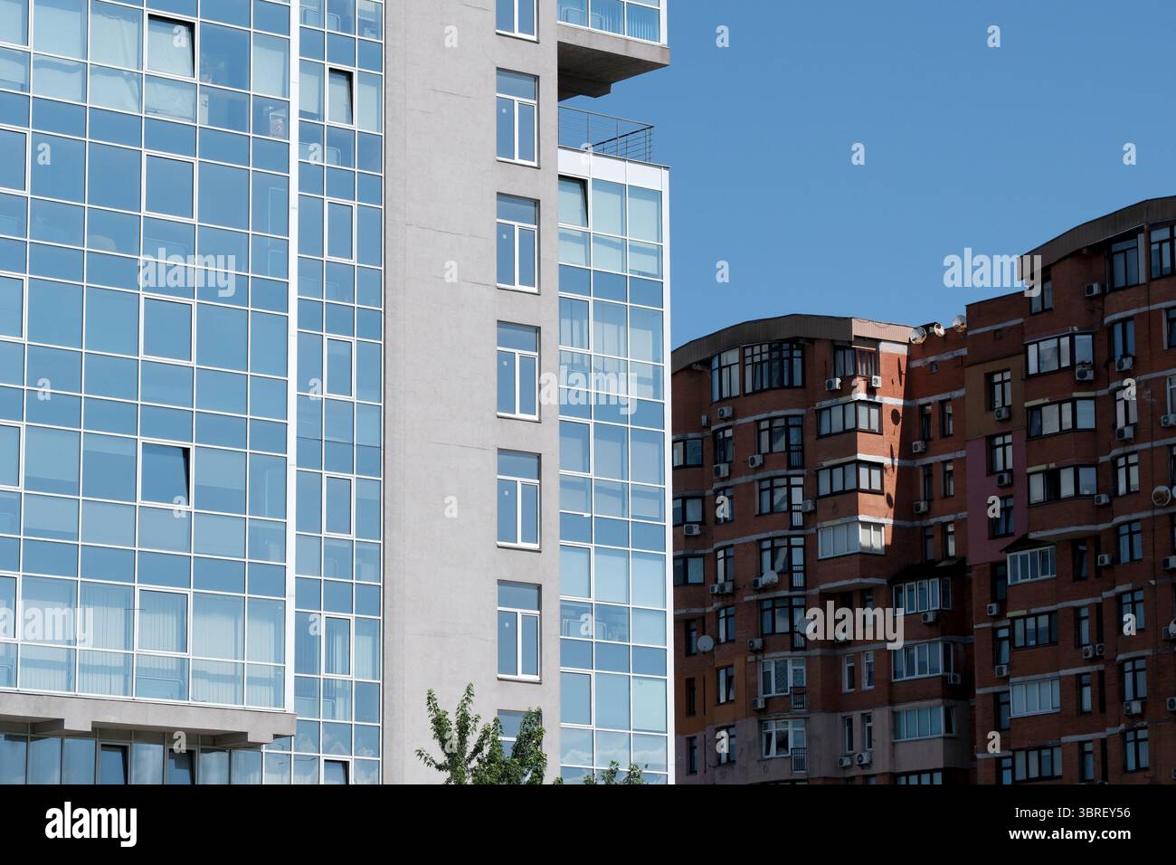 Due edifici a contrasto mostrano stili architettonici sotto un cielo azzurro. Foto Stock
